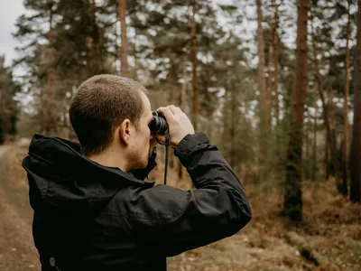 Hunter glassing a valley from a rocky overlook